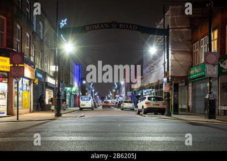 Londres, Angleterre, Royaume-Uni - 2 janvier 2020: Les piétons marchent devant les magasins et les restaurants de Roman Road dans le quartier East End de Londres la nuit. Banque D'Images