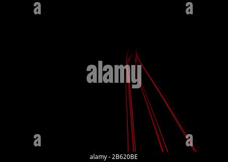 détail des sentiers des ampoules de feux arrière des véhicules traversant sur une route la nuit Banque D'Images