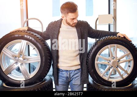 Homme barbu agréable toucher et choisir pour acheter un pneu dans un supermarché ou un magasin de bricolage, gros plan photo. Banque D'Images