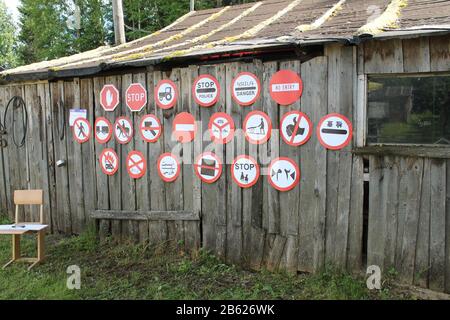 De nombreux panneaux routiers pendent sur le mur d'un bâtiment rural en bois avec une fenêtre. Décoration d'art contemporain. Syktyvkar, Russie, Barkemp. Banque D'Images