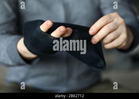 L'homme passe les doigts dans le grand trou de la chaussette noire Banque D'Images
