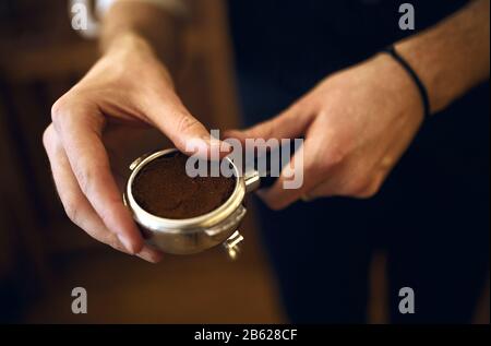 le propriétaire du café tient un filtre à hublot contenant du café fraîchement moulu, une photo de vue latérale rapprochée, un arrière-plan flou.composant nécessaire qui est par Banque D'Images