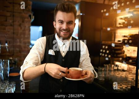 l'homme positif prépare et vend des boissons à base de café en suivant les recettes prescrites et les techniques de préparation pour les boissons à base de café, photo de gros plan Banque D'Images