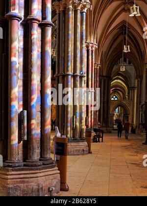 Les vitraux de la cathédrale de Lincoln ont jeté des couleurs tachetées sur les colonnes de la nef lors d'une journée de printemps. Banque D'Images