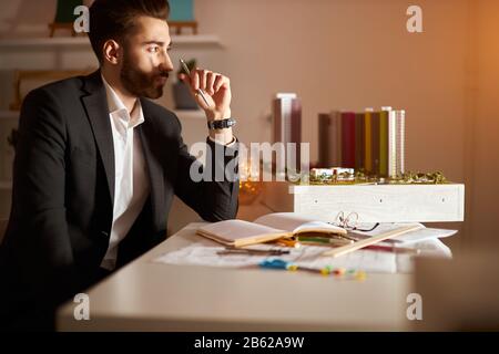 jeune homme intelligent prépare des dessins et un rapport présentant des idées pour le client à examiner, gros plan de la photo. guy à la recherche de l'inspiration Banque D'Images