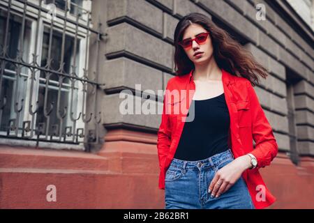 Mode féminin de rue. Portrait d'une jeune femme taille élégante portant des lunettes de chemise rouge à l'extérieur. Accessoires de ressort Banque D'Images