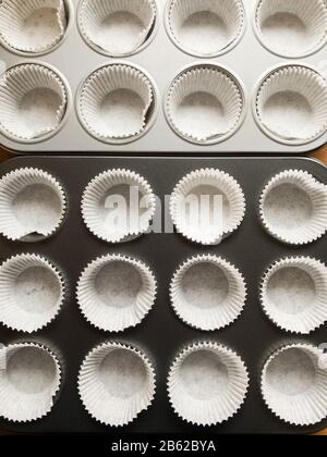 Gros plan du moule à muffins à cupcakes avec des formulaires en papier vides, préparation à la cuisson dans la cuisine, directement au-dessus de la vue du dessus Banque D'Images