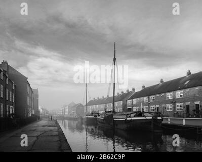 Des barges restaurés amarrés le long du beck (canal) dans un matin calme et lumineux au printemps flanqué de maisons de ville à Beverley, Yorkshire, Royaume-Uni. Banque D'Images