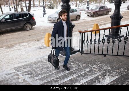 jeune homme d'affaires ayant réussi à monter les escaliers, photo pleine longueur. homme se précipitant pour travailler. Banque D'Images