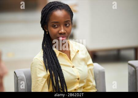 jeune femme afro-américaine sérieuse pensive et réfléchie dans un élégant maillot jaune regardant de côté, pensant à son entreprise, la planification de son jour, Banque D'Images