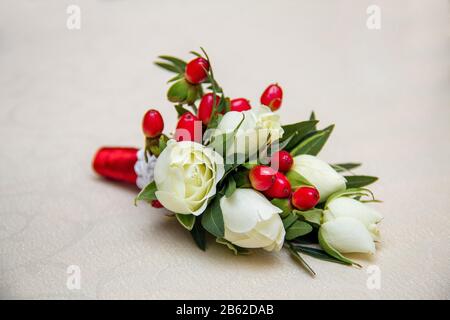 Magnifique boutonnière de mariage de fleurs de varios sur fond blanc en bois. Banque D'Images