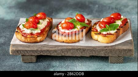 Bruschettas italiens avec mozzarella, riccotta, tomates cuites et basilic Banque D'Images