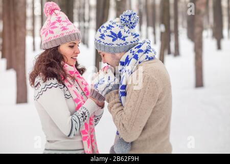 copain réchauffe les mains petite amie, gelée dans le froid parc d'hiver. Banque D'Images
