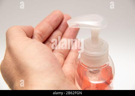 Aseptisant à main rose clair dans un flacon de pompe transparent isolé. L'assainisseur pour les mains est utilisé pour tuer les germes, le coronavirus, etc Banque D'Images