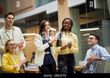 Excellent concept de teambuilding d'emploi. Une équipe d'affaires réussie se claque les mains dans le bureau moderne , célébrant la présentation du nouveau produit.,bonheur Banque D'Images