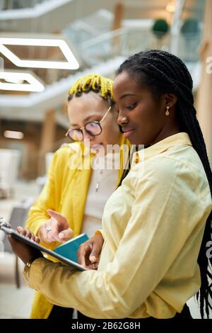 afro attrtiva crème anglaise en jaune élégant blose consultant client, gros plan photo, belle femme pointant vers le document qui est Banque D'Images