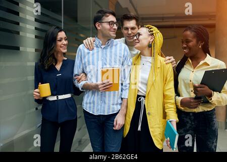 des étudiants de course mixtes qui renagent à la maison après des cours, des cours, des conférences, des employés de bureau ayant une conversation agréable tout en marchant au bureau. amitié, bon rel Banque D'Images
