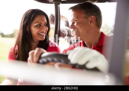 Couple D'Âge Mûr Jouant Au Golf Conduisant Buggy Le Long Du Parcours À Green Le Jour De La Lettre Rouge Banque D'Images