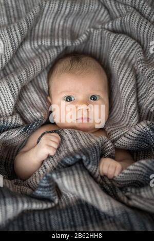 Jolie fille de bébé nouveau-né, enveloppée dans une couverture, posée dans le lit Banque D'Images
