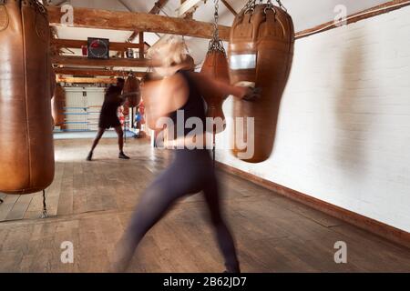 Action Shot Of Male And Féminin Boxers In Gym Training With Leather Punch Sacoches Banque D'Images