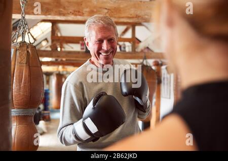 Senior Boxer Sparring Avec Entraîneur Femelle Jeune Dans La Salle De Gym Utilisant Des Gants D'Entraînement Banque D'Images