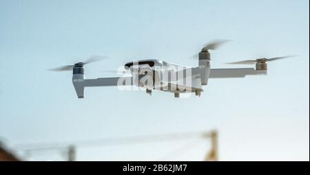 Un drone quadricoptère avec caméra se bloque dans l'air contre un ciel bleu. Prendre des photos et des vidéos à partir de l'air à l'altitude. Technologies modernes de l'unma Banque D'Images