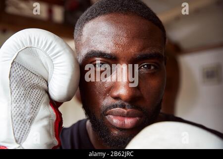 Gros Plan Portrait De Boxer Masculin Dans La Salle De Gym Portant Des Gants De Boxe Banque D'Images
