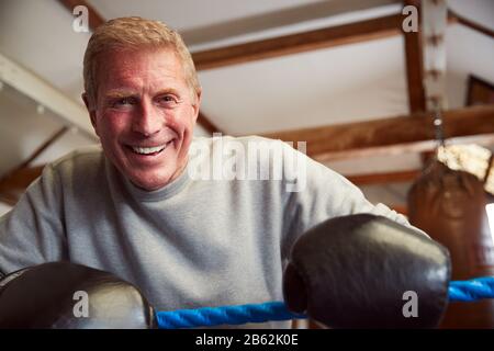 Caleçons Hommes Souriants En Salle De Gym Portant Des Gants De Boxe Penchant Sur Des Cordes De Boxe Ring Banque D'Images