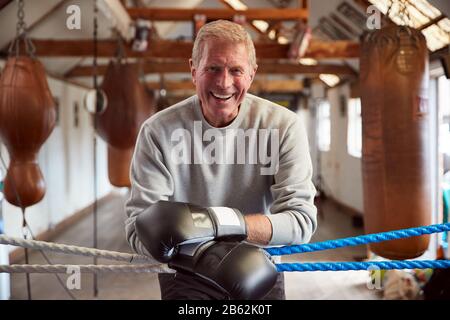 Caleçons Hommes Souriants En Salle De Gym Portant Des Gants De Boxe Penchant Sur Des Cordes De Boxe Ring Banque D'Images