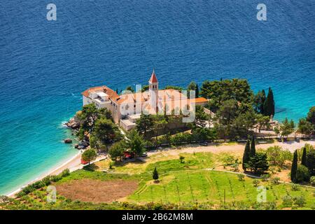 Voir de belle baie avec plage et monastère dominicain de la ville de Bol, Île de Brac, Croatie. Monastère dominicain dans Bol, construit au 15e siècle. Remorquage de bol Banque D'Images