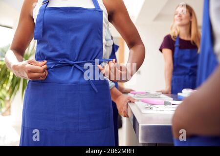 Gros Plan De La Femme Qui Joue À L'Apron En Prenant Part À La Classe Cookery Dans La Cuisine Banque D'Images