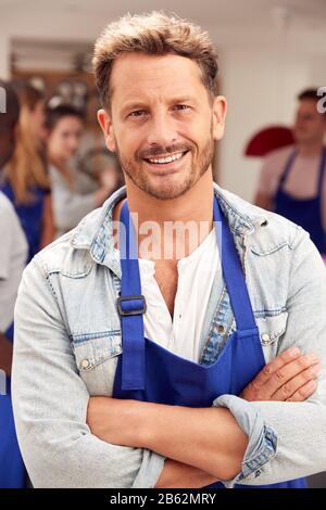 Portrait De Smiling Homme D'Âge Mûr Portant Un Tablier Prenant Part À La Classe Cookery Dans La Cuisine Banque D'Images