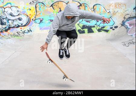 jeune patineuse faisant un tour de saut au skate park . Banque D'Images