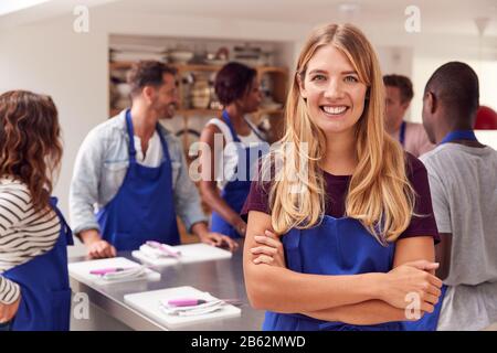 Portrait De La Femme Smiling Portant Un Tablier Prenant Part À La Classe Cookery Dans La Cuisine Banque D'Images