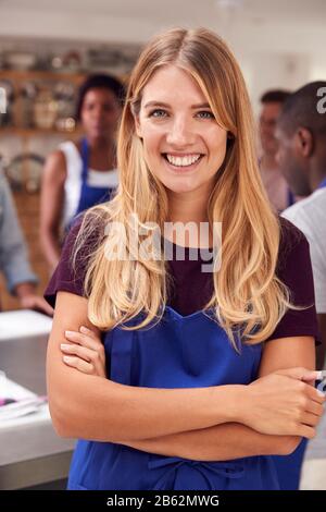 Portrait De La Femme Smiling Portant Un Tablier Prenant Part À La Classe Cookery Dans La Cuisine Banque D'Images