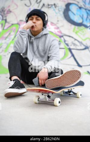 Jeune patineur latin posant avec skateboard au skate Park . Banque D'Images