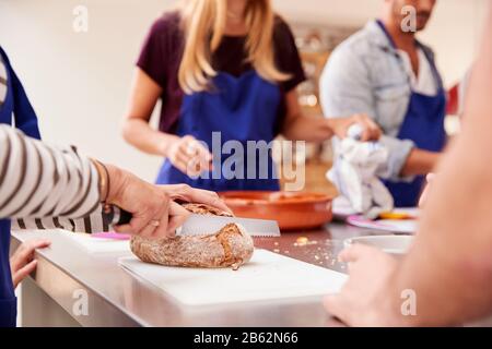 Proche De La Femme Tranche De Pain Pendant Que Les Élèves Préparent Des Ingrédients Pour Le Plat Dans La Cuisine Cookery Class Banque D'Images