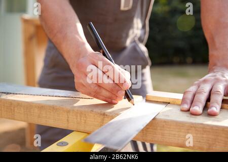 Gros Plan Carpenter Mâle Mesurant Le Bois À L'Aide De Set Square À L'Extérieur Banque D'Images