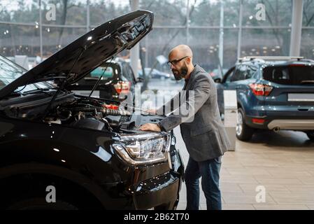 Homme dans un nouveau chariot avec capot ouvert, concessionnaire automobile Banque D'Images