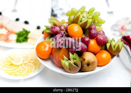 Plateau de fruits coloré avec mandarines et raisins kiwis Banque D'Images