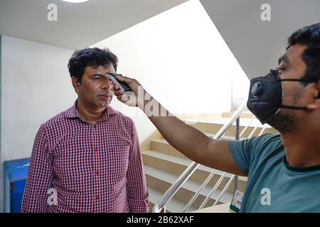 Dhaka, Bangladesh. 9 mars 2020. Un homme bangladais utilise un thermomètre infrarouge pour vérifier la température d'un visiteur qui arrive à un bureau d'entreprise à Dhaka, au Bangladesh, le 09 février 2020. Le Bangladesh a annoncé les premiers cas confirmés de coronavirus dans le pays après que trois personnes ont testé un virus infectieux positif dans la capitale Dhaka dimanche. Crédit: Suvra Kanti Das/Zuma Wire/Alay Live News Banque D'Images
