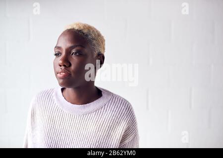 Portrait De La Jeune Femme Debout Contre Le Mur De Studio Blanc Banque D'Images