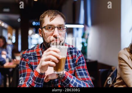 Hipster Man dans les verres est boire du café dans le café Banque D'Images