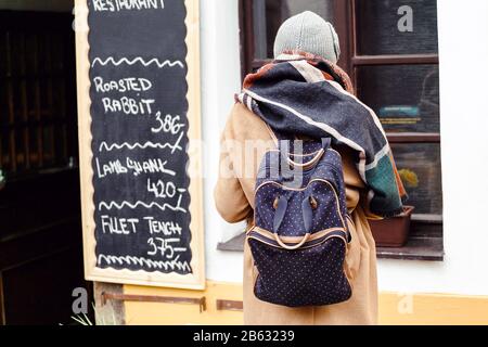Femme touriste avec sac à dos à l'automne regardant le menu du restaurant avec le prix en Europe Banque D'Images