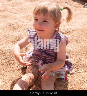 Heureuse petite fille jouant dans un grain, Elle est souriante et regarde heureux Banque D'Images