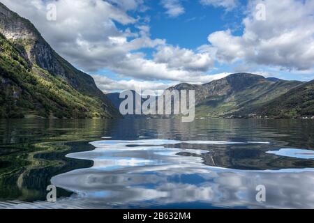 Vue depuis la surface de l'eau avec réflexion vive. Norvège Voyage dans le fjord d'Aurlandsfjord, excursion en kayak. Nature, montagnes, paysage bleu, vue épique nuageux. Banque D'Images