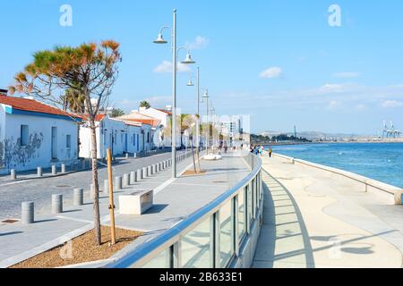 Les gens qui marchent à proximité de la ville de Larnaca embankment avec des bâtiments typiques d'architecture de couleur blanche dans le soleil lumineux, Chypre Banque D'Images