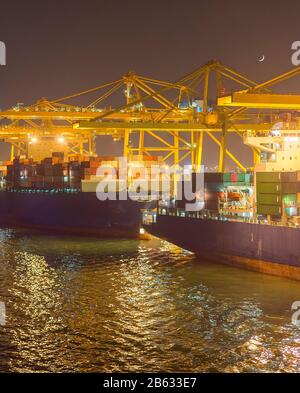 Des cargos, des grues et des conteneurs au port industriel de nuit. Barcelone, Espagne Banque D'Images