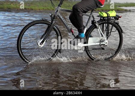 Cycliste mâle qui traverse les eaux de crue de Knavesmire Road, York, Royaume-Uni pendant les inondations de 2020. Banque D'Images