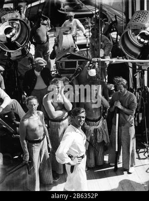 Clark A PIGNON en costume comme Fletcher Christian fumant avec l'équipage du film et des acteurs dont EDDIE QUILLAN pendant la pause dans le tournage de LA MUTINERIE SUR LE METTEUR en scène DE 1935 FRANK LLOYD book Charles Nordhoff et James Norman Hall Metro Goldwyn Mayer Banque D'Images